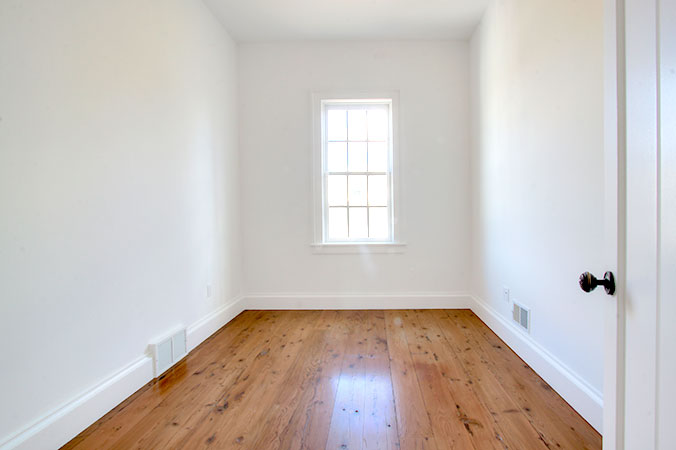 Bedroom with window, white walls and hardwood floors