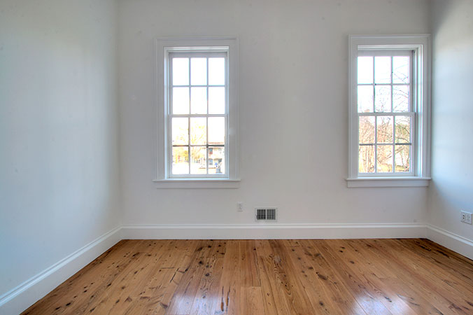 Two window bedroom with white walls and hardwood floors
