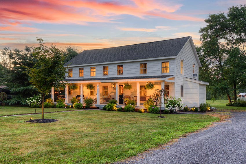 Historic farmhouse with a rocking chair porch that spans the entire front of the house