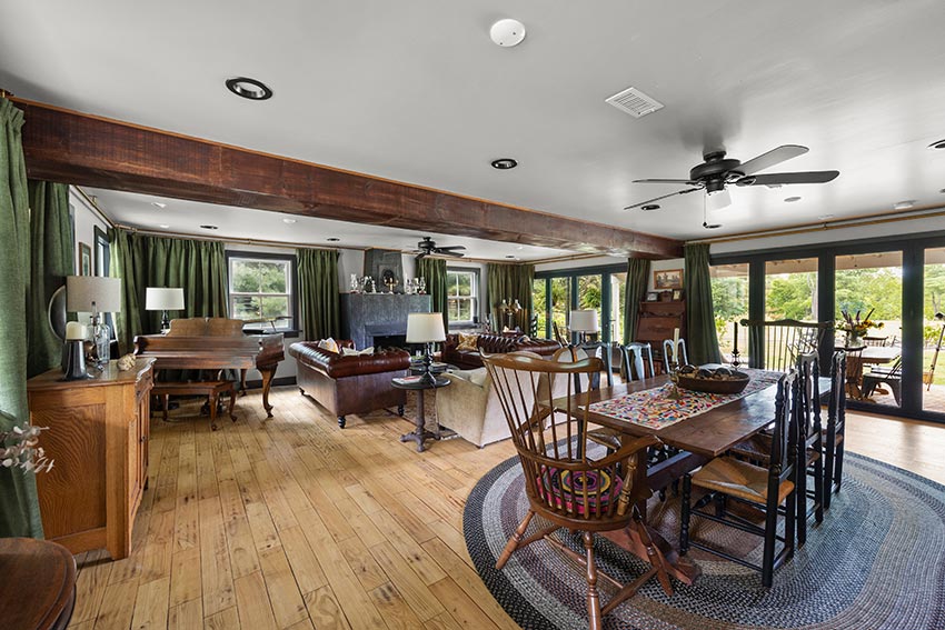 A vast living room area, dining room & a wall of glass doors that opens onto a covered porch