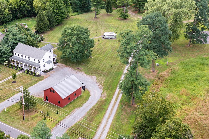 Aerial view of beautifully landscaped green space with a large heated red barn-style garage