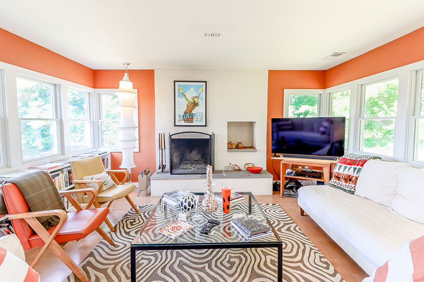 Light filled living room with wood burning fireplace and designer furniture.