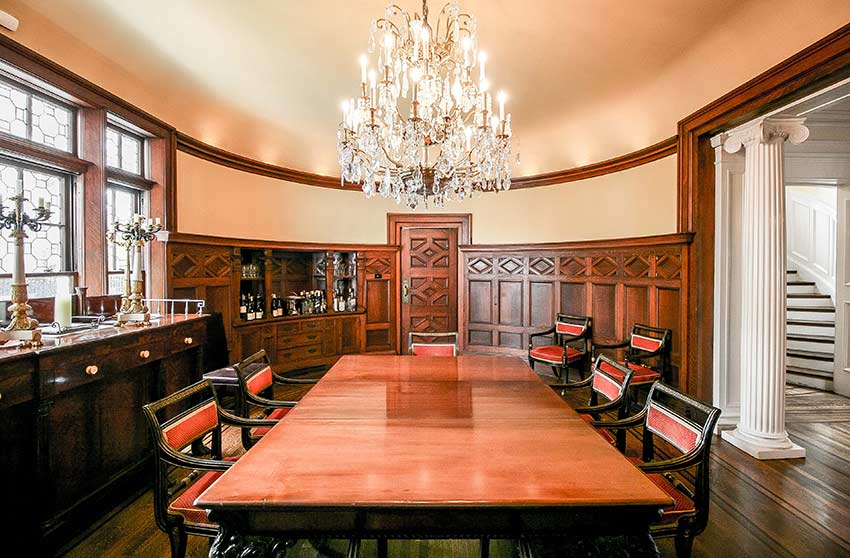 Formal oak paneled dining room features a gorgeous crystal chandelier and fireplace